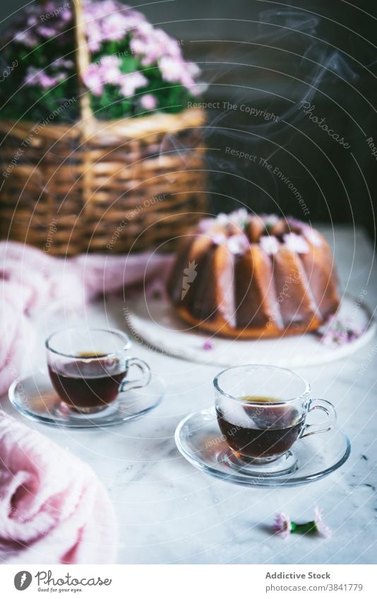 Tassen Tee auf dem Tisch mit süßem Gugelhupf heiß Kuchen Dessert Ordnung Bundkuchen Leckerbissen trinken lecker Tradition Becher Glas frisch dienen appetitlich