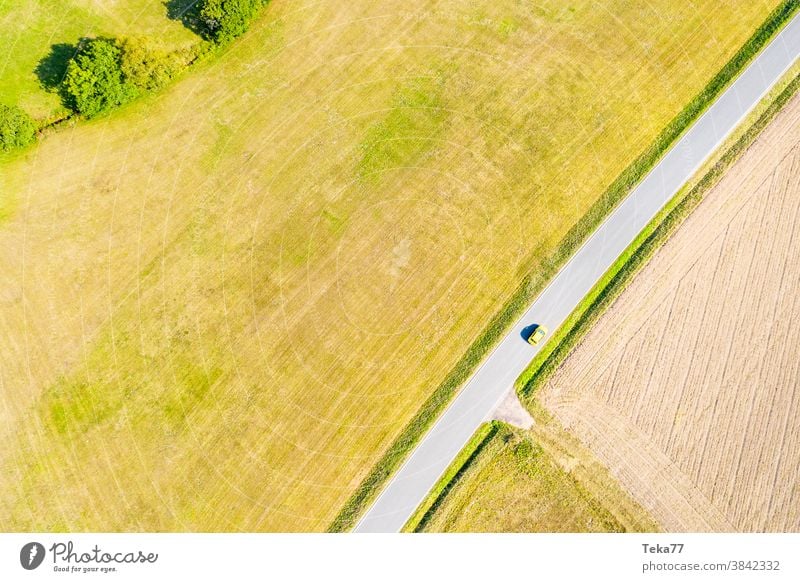 ein gelbes Auto auf einer Landstraße im Sommer von oben td von oben nach unten Verkehr ländliche Gebiete einsam Auto von oben Beton Wiese