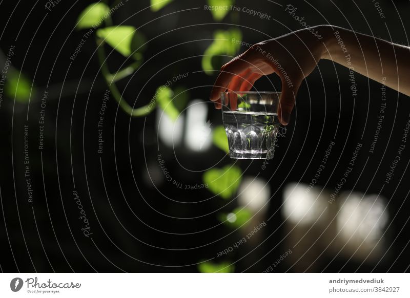 Frau hält ein Glas Wasser auf dunklem Hintergrund. Glas mit reinem Wasser in der Hand. Gesunder Lebensstil. Ökologie Sauberkeit übersichtlich Arme Getränk
