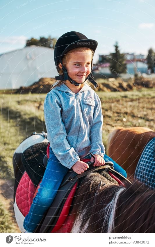 Kleines lächelndes Mädchen lernt Reiten Kind Mitfahrgelegenheit Pferd üben Schule niedlich Land hübsch ländlich Ranch Lektion Reiter Fröhlichkeit lernen