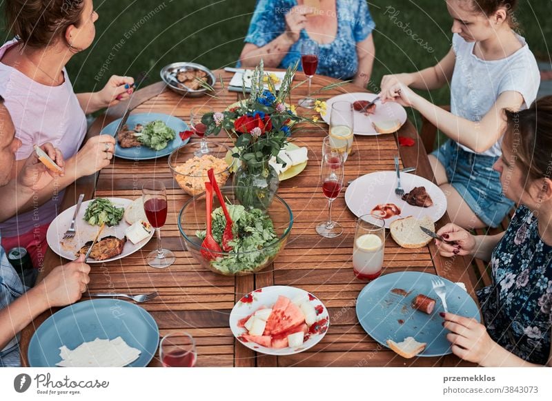 Familie isst während des Sommerpicknicks im Freien in einem Hausgarten zu Abend heimwärts Festessen habend Picknick Lebensmittel Mann Zusammensein Frau Kind