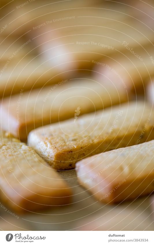 Gebäck liegt geordnet auf Backpapier Keks Plätzchen Teig Nudelholz Backwaren Lebensmittel Ernährung backen Nahaufnahme süß lecker Weihnachtsgebäck