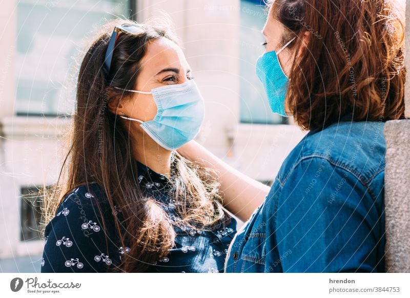 Paar Frauen mit Gesichtsmaske, die sich auf der Straße umarmen lesbisch Homosexualität Coronavirus Liebe Bund 19 Freundin Glück umarmend Lifestyle Romantik