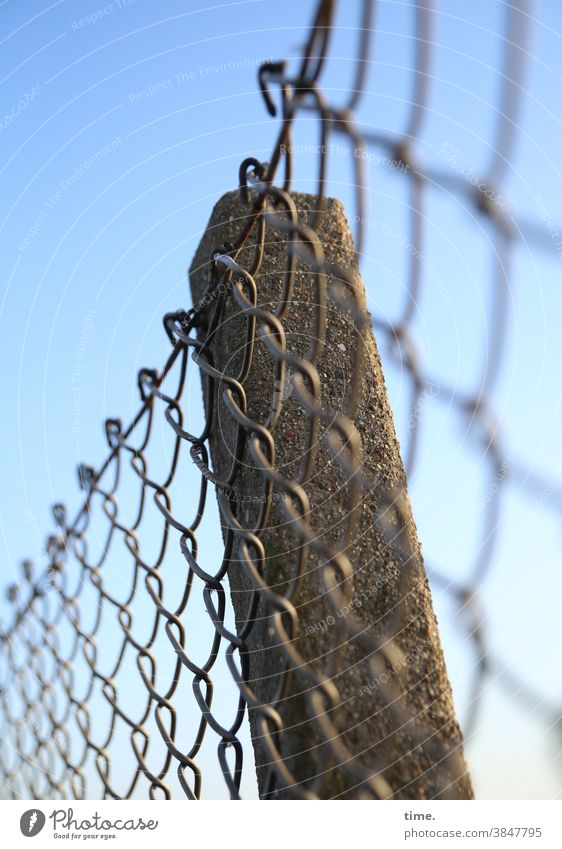 Geschichten vom Zaun (82) zaun betonpfeiler himmel sonnig sonnenlicht maschendraht Maschendrahtzaun linien streifen schräg alt