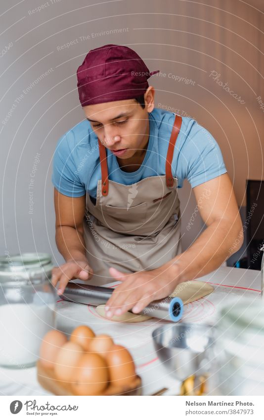 Mann, der Teig über einen weißen Tisch knetet. Erwachsener im Innenbereich Essen zubereiten Teigwaren Mehl Küchenchef Restaurant Beschäftigung Lebensmittel Eier