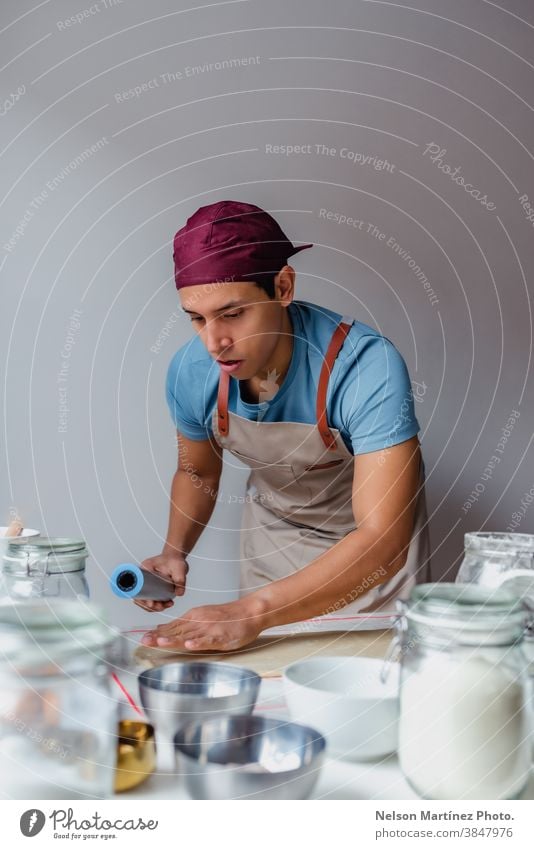 Mann, der Teig über einen weißen Tisch knetet. Erwachsener im Innenbereich Essen zubereiten Teigwaren Mehl Küchenchef Restaurant Beschäftigung Lebensmittel Eier