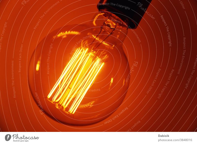 Vintage-Glühbirne auf orangem Hintergrund, Nahaufnahme. Glühende Edison-Glühbirne Knolle Licht altehrwürdig Lampe Design weiß kreativ Konzept Idee Farbe