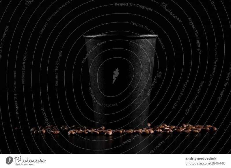 schwarzes Papierglas auf schwarzem Hintergrund. Kaffeebohnen auf dunklem Hintergrund. guten Morgen Bohnen Tasse dunkel braun Glas heiß trinken Getränk Becher