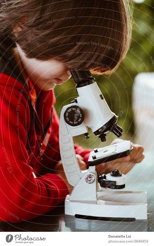 Kind schaut durch ein Mikroskop Aufmerksamkeit Freizeitkleidung Kaukasier Kindheit Konzept Neugier neugierig erkunden Lernen Lifestyle Blick männlich Natur eine