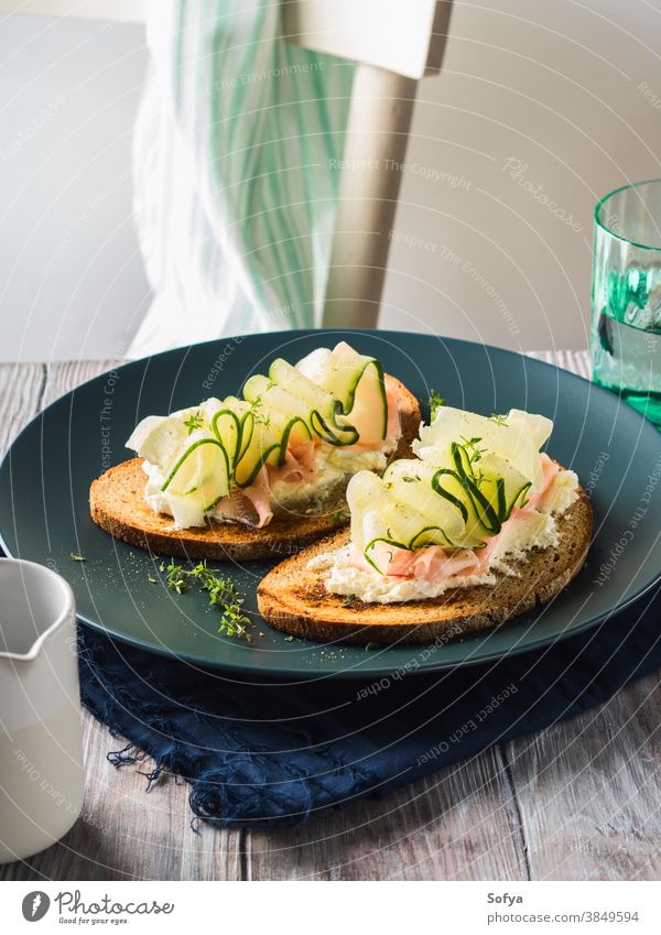 Roggenbrottoasts mit Käse, Schinken, Gurke Belegtes Brot Lebensmittel Salatgurke Gemüse Zuprosten frisch Scheibe Frühstück Kulisse Tisch hölzern schwarz Speise