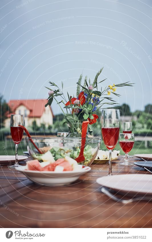 Abendessen in einem Apfelgarten auf einem Holztisch mit Salaten und Wein, dekoriert mit Blumen heimwärts Festessen Picknick Lebensmittel Sommer Barbecue Tisch