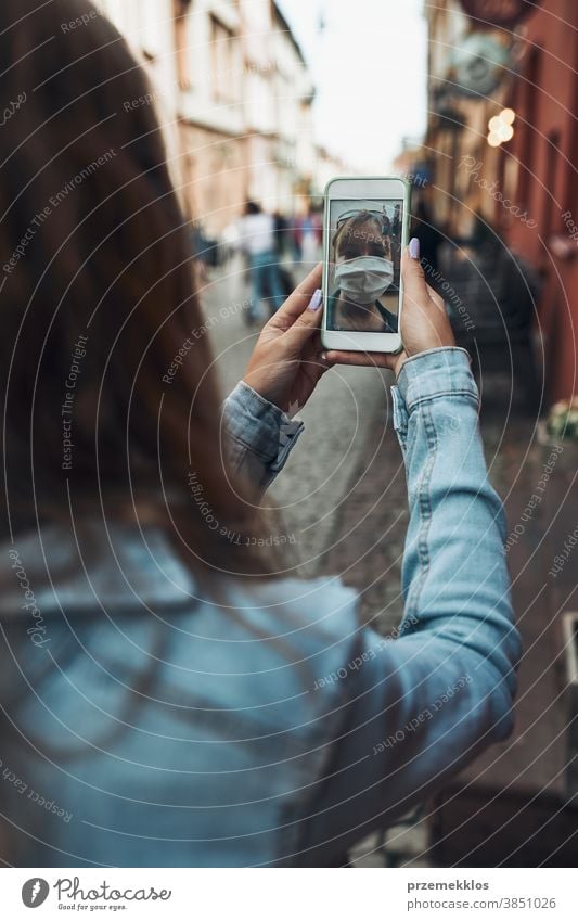 Junge Frau führt Videoanrufgespräche, während sie mit der Gesichtsmaske in der Innenstadt läuft, um eine Virusinfektion zu vermeiden Anruf Pflege Kaukasier