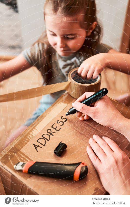 Frau schreibt eine Adresse auf ein Karton-Paket, das zum Versand vorbereitet wird Ansicht Stock Geschenk Auspacken Klebeband Mädchen Tochter Füller schäumen