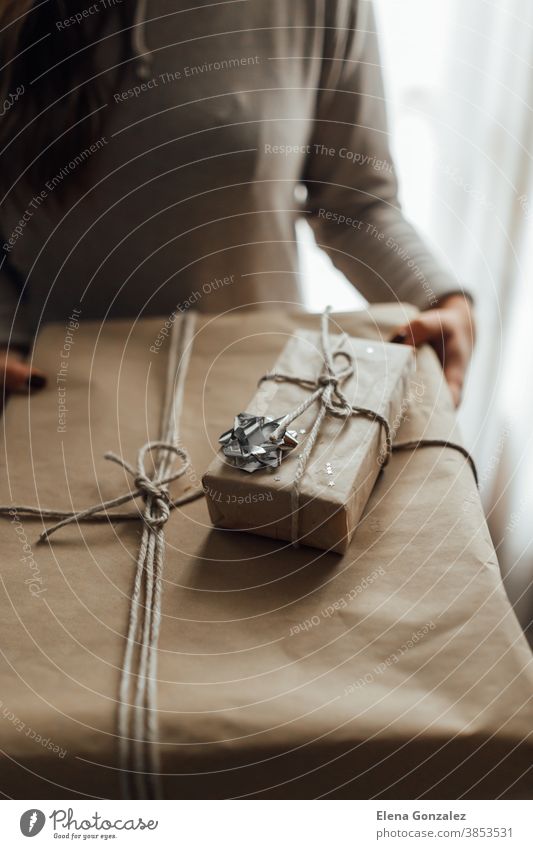 Junge Frau hält in den Händen gestapelte Weihnachtsgeschenkkartons aus Bastelpapier mit Wacholder. Konzept der Weihnachtsgeschenke. Weihnachten