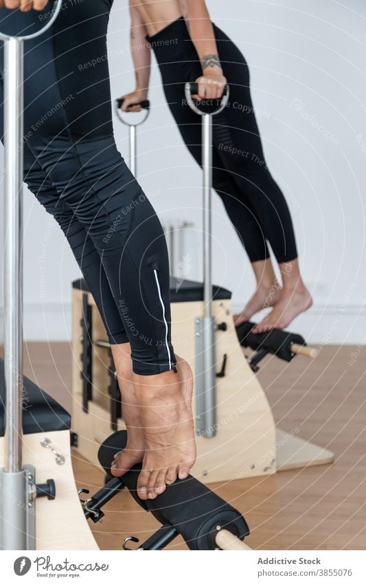 Crop-Sportler bei Übungen auf Pilates-Stühlen Stuhl üben Training Sportlerin Gleichgewicht Fitnessstudio Gesundheit Athlet Wellness passen Sportbekleidung