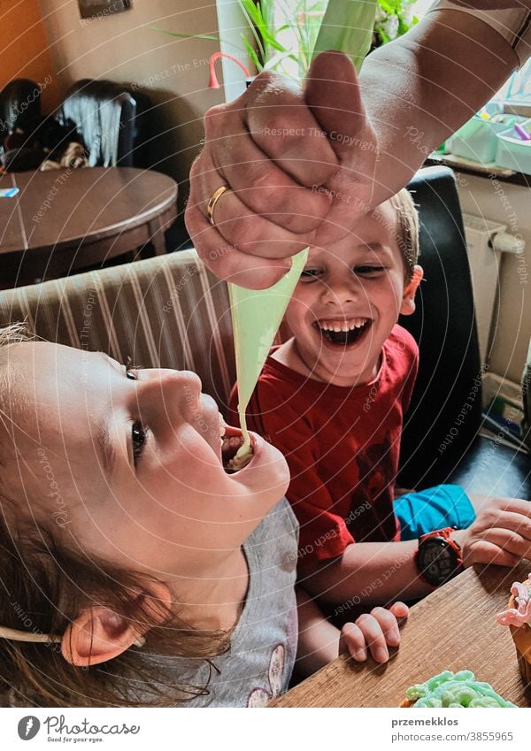 Kind isst Schlagsahne, die direkt aus der Tüte gepresst wurde Kinder backen Cupcake dekorierend Keks vorbereitend Essen zubereiten Familie heimisch Muffin