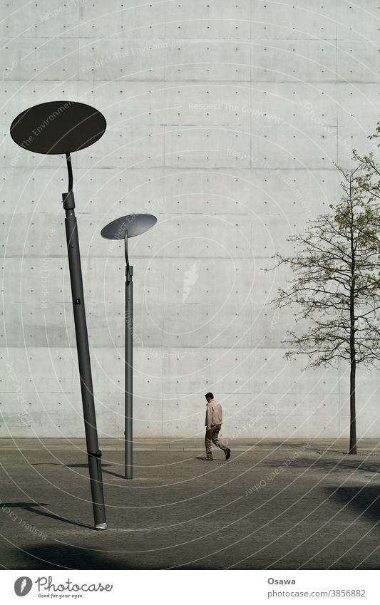 Gebeugter vor Gebäude Stadt Architektur Fassade Mauer Wand Sichtbeton Laternen schief Mann Baum Stadtbaum kahl Textur Stein Außenaufnahme Bauwerk Haus Beton