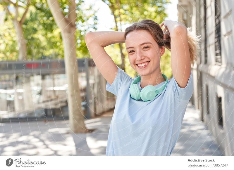 Fröhlicher weiblicher Teenager mit Kopfhörern auf der Straße stehend Mädchen Glück urban Sommer Freude Lächeln Spaß haben Frau Schüler Großstadt modern jung