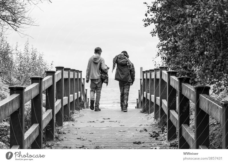 Zwei Freunde brechen zu einem Strandspaziergang auf, gegen jedes Wetter gewappnet Jungs Kinder Jugendliche Düne Strandaufgang Wind Regen Herbst kalt windig