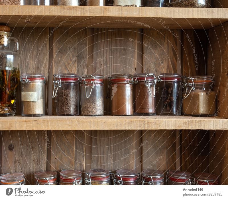 Flaschen mit Gewürzen und Würzmitteln im Holzgestell. Verschiedene verschiedene Bio-Kräuter für den Vintage-Look in der Küche Ablage Lebensmittel Kraut Paprika