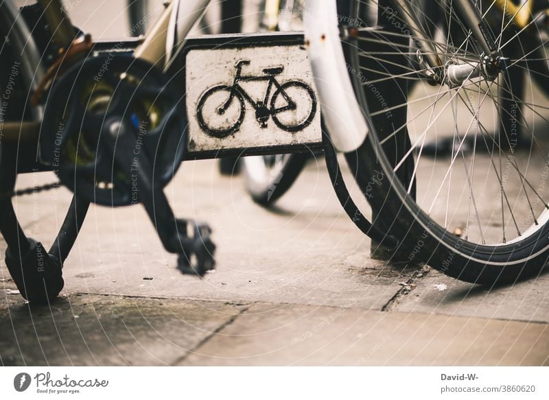 abgeschlossenes Fahrrad und ein Schild auf dem ein Rad abgebildet ist Schloss stehen parken Stadt Verkehrsmittel Zeichen