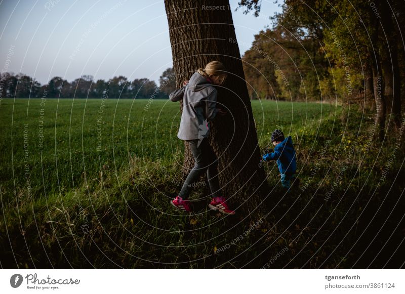 Versteckspiel beim Abendspaziergang Kinder Kinderspiel verstecken Abenddämmerung Außenaufnahme Kindheit Spielen Freude Farbfoto Glück Fröhlichkeit niedlich