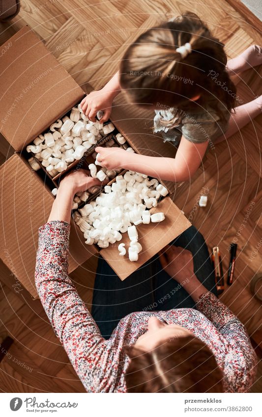 Frau packt mit Hilfe ihrer Tochter ein Pappkarton-Paket aus Ansicht Stock Geschenk Auspacken Klebeband Mädchen Füller schäumen Rudel Top offen Kasten auspacken