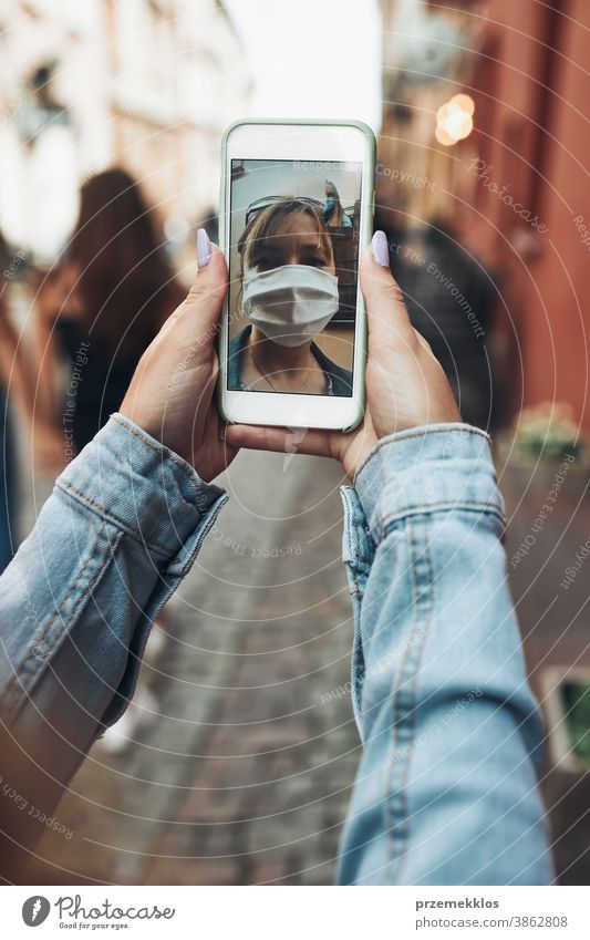 Junge Frau führt Videoanrufgespräche, während sie mit der Gesichtsmaske in der Innenstadt läuft, um eine Virusinfektion zu vermeiden Anruf Pflege Kaukasier