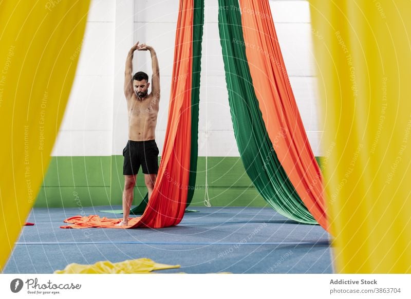 Shirtless männlichen Tänzer Stretching Arme in der Nähe von Antenne Seiden Mann Dehnung Probe Atelier Arme hochgezogen Aufwärmen üben beweglich Erwachsener