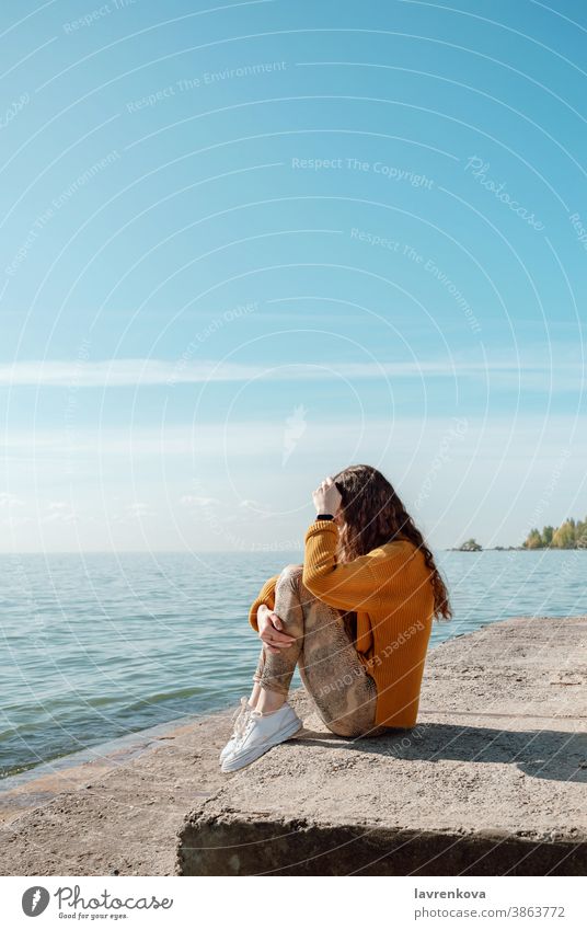 Weibliche Person sitzt auf einer Steintreppe am Strand und umarmt ihre Knie Frau MEER sich[Akk] entspannen Lifestyle Freizeit Meer Wasser im Freien Pullover