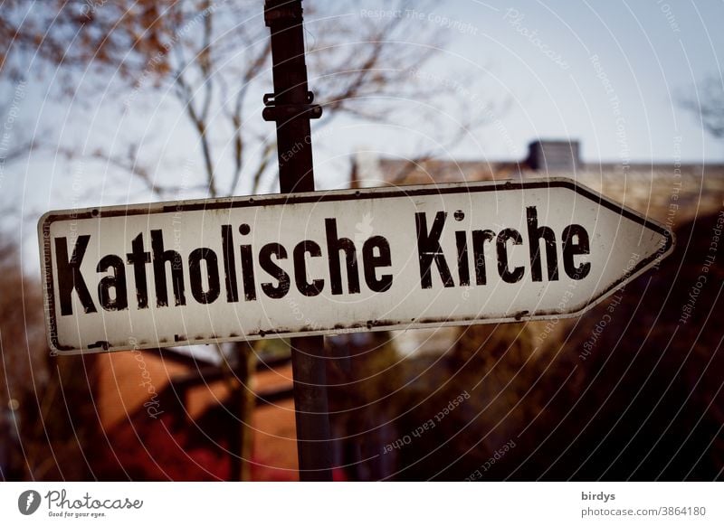 Richtungsweisendes Straßenschild mit der Aufschrift " Katholische Kirche ". Katholische Kirche katholische Kirche Katholizismus Zölibat Mißbrauch düster Schrift