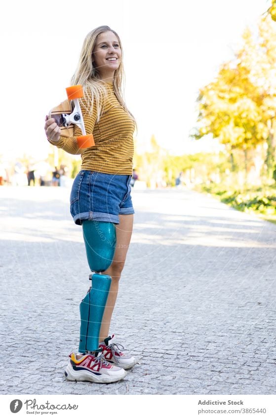 Schlanke Frau mit Longboard und Beinprothese auf der Straße Prothesen Bionik Skater künstlich Glied deaktivieren urban Skateboard Stadt modern Sonnenlicht