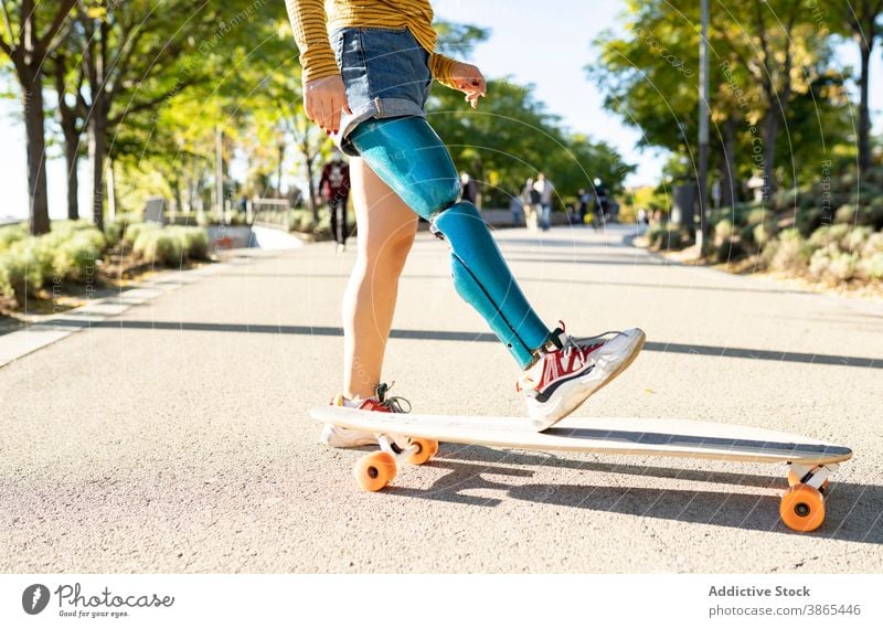 Crop Frau Reiten Longboard in der Stadt Bionik Prothesen Mitfahrgelegenheit Skater Bein heiter deaktivieren künstliches Glied Amputierte Straße urban Optimist