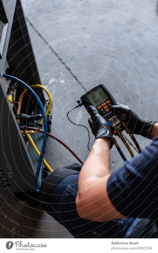 Mann beim Prüfen der Spannung einer defekten Maschine Mechaniker prüfen Tester modern gebrochen Werkstatt Arbeit Gerät männlich Schutzbrille Handschuh manuell