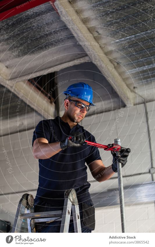 Arbeiter bei der Installation von Rohren mit Schraubenschlüssel in der Werkstatt Röhren Klempner installieren Handwerker Werkzeug Mann professionell heiter