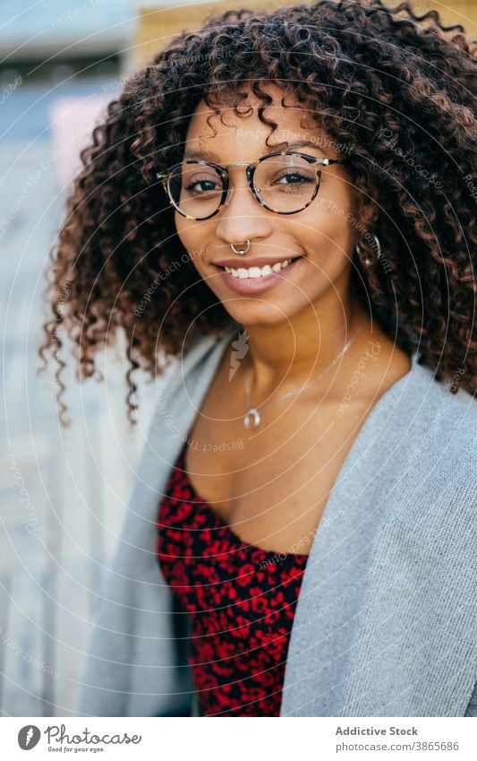 Fröhliche schwarze Frau sitzt auf Böschung Stauanlage MEER Lächeln Stil Wochenende Glück Outfit ruhen jung Kai heiter ethnisch Afroamerikaner sitzen Wasser