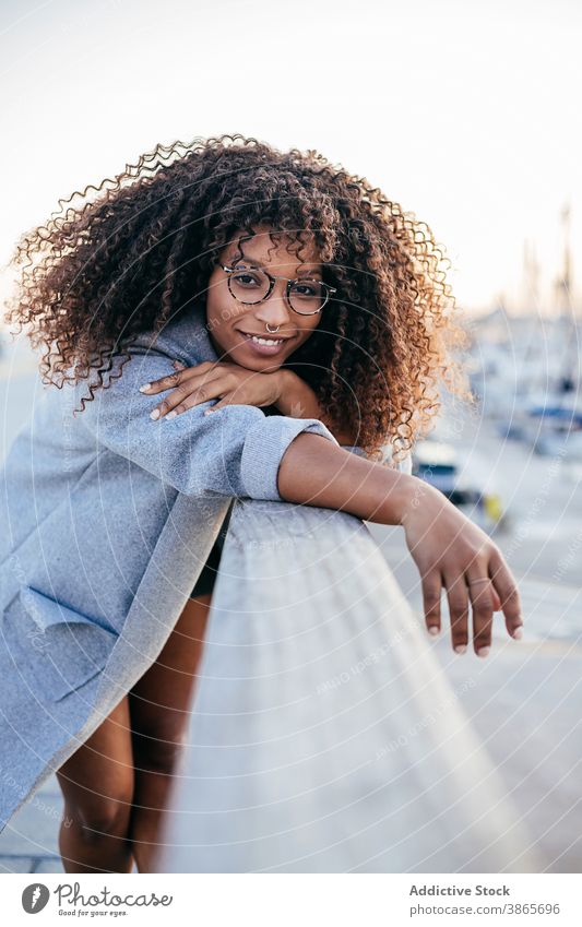 Fröhliche schwarze Frau lehnt an der Reling im Hafen fettarm Zaun Portwein Lächeln ruhen Großstadt Stil Glück modern ethnisch positiv Afroamerikaner heiter froh