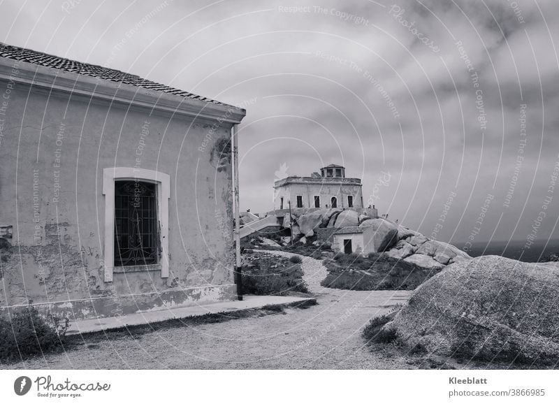 Schwarzweiß Aufnahme - Weg zu einem alten Leuchtturm auf Sardinien Capo Testa bei regenverhangenem Himmel Schwarzweißfoto regenverhangener Himmel Meer