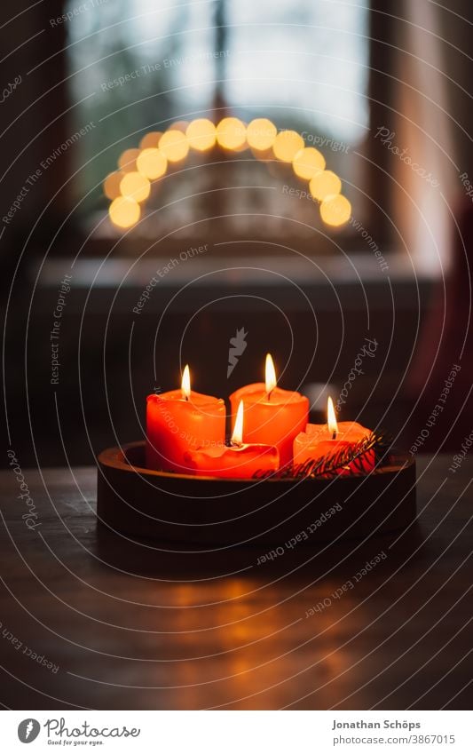 Adventskranz mit brennenden roten Kerzen auf Holztisch stehend im Wohnzimmer mit Kerzenbogen im Fenster hell Christentum Weihnachten Weihnachten & Advent