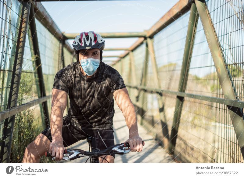 Biker mit Gesichtsmaske trainiert Sport in Pandemiezeiten Männer covid-19 Corona-Virus coronaviorus Mundschutz Fahrrad Schutzhelm im Freien Mann Erwachsener Tag