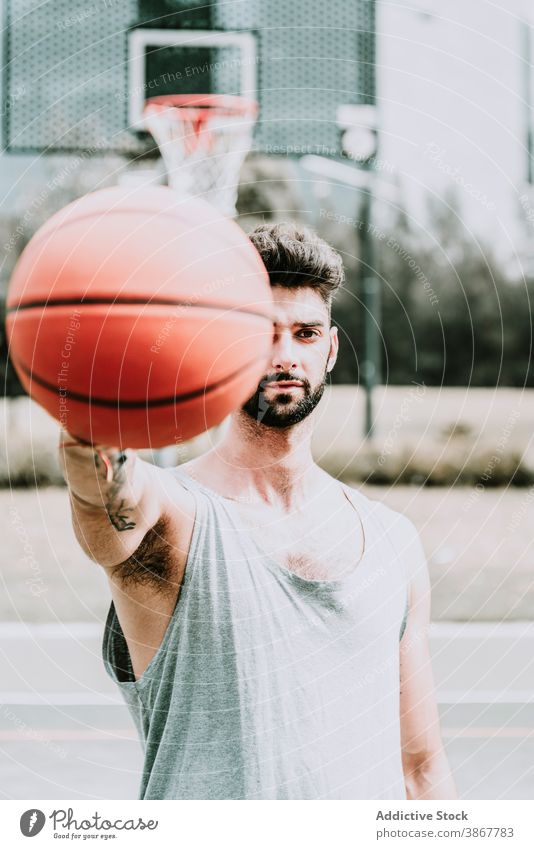 Junger Mann mit Basketball auf Sportplatz Ball selbstbewusst Spieler Streetball Sportpark Vollbart jung ernst Training Spielplatz Athlet Aktivität Lifestyle