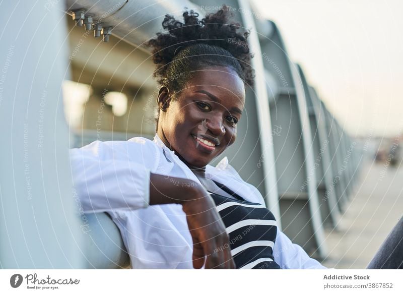 Lächelnde afroamerikanische Frau, die sich auf der Straße ausruht heiter Glück urban jung genießen positiv ruhen Inhalt Afro-Look schwarz Schüler Afroamerikaner