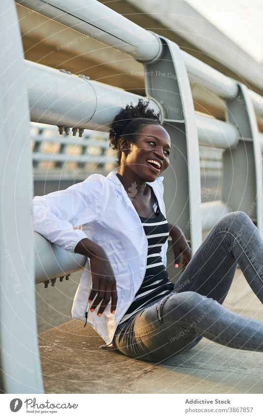 Lächelnde afroamerikanische Frau, die sich auf der Straße ausruht heiter Glück urban jung genießen positiv ruhen Inhalt Afro-Look schwarz Schüler Afroamerikaner