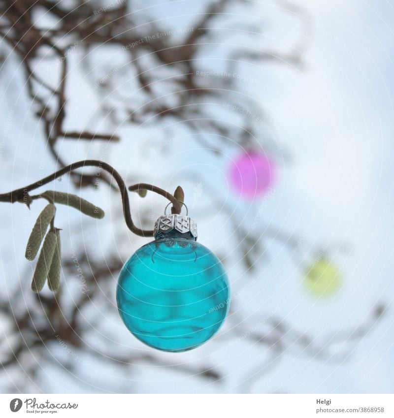 blaue Glaskugel hängt an einem kahlen Zweig der Korkenzieherhasel, im Hintergrund zwei weitere unscharfe Kugeln und Zweige Weihnachtsbaumkugel Weihnachtsschmuck