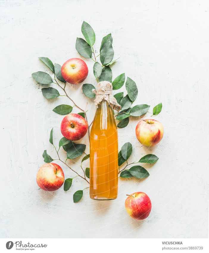 Hausgemachter Apfelessig in Flasche mit Äpfeln und grünen Blättern auf weißem Hintergrund. Ansicht von oben selbstgemacht Essig Apfelbaum Zweige Muster