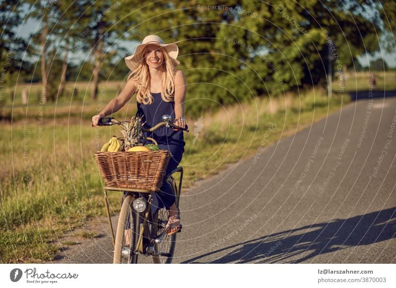 Porträt einer schönen Frau, die glücklich lächelt, während sie ein gestreiftes Hemd trägt und an einem sonnigen Tag auf dem Land Fahrrad fährt Gesicht Sommer