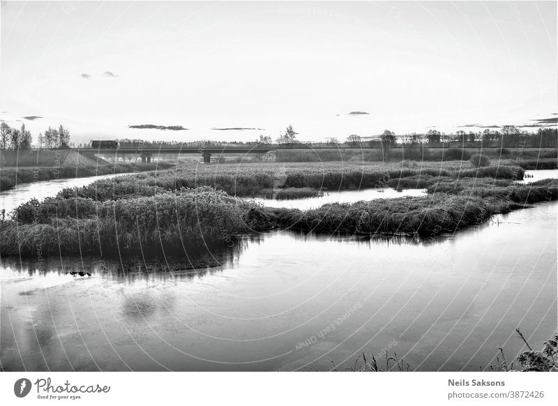 schwarz-weiße Landschaft mit Autobahnbrücke über den Fluss in Lettland. Kurz vor Beginn des Winters. Hintergrund schön blau Brücke Küste Küstenstreifen kalt Tag