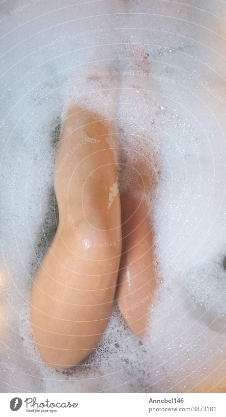 Frauenbeine in der Badewanne, Baden mit Sprudelbadschaum von oben, Entspannungs-Schönheitsspa-Konzept Pflege Hygiene Seife schäumen Körper jung Erholung Wasser