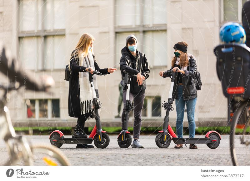 Trendige, modische Gruppe von Freunden, die auf öffentlichen Miet-Elektrorollern in der städtischen Umgebung fahren. Neuer umweltfreundlicher, moderner öffentlicher Stadtverkehr in Ljubljana, Slowenien.