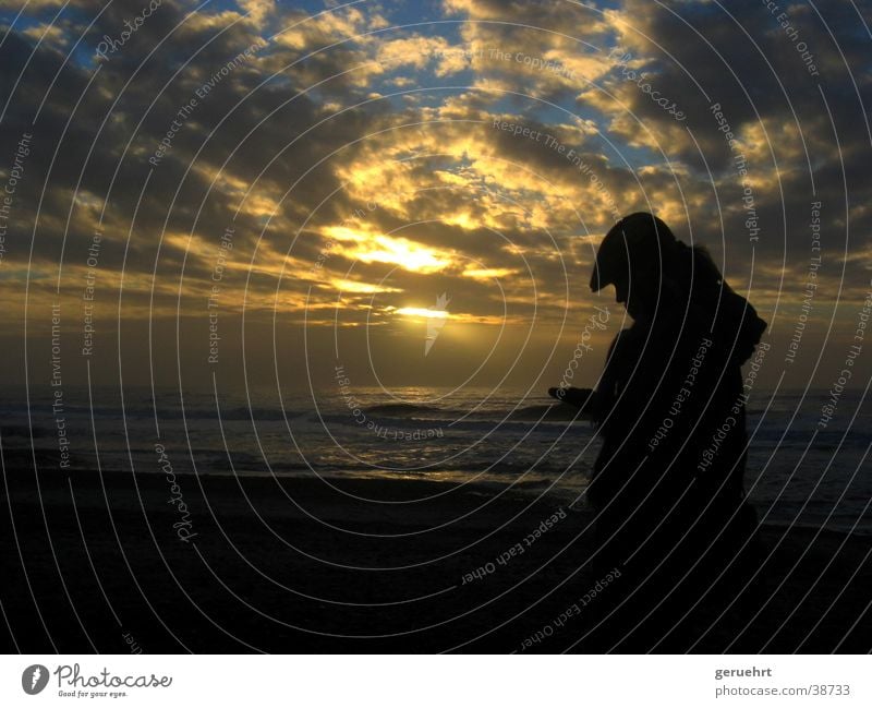 frau gegen licht Wellen Küste Strand Sonnenuntergang Dämmerung Wolkenformation Reflexion & Spiegelung Gegenlicht Silhouette Frau Mütze Kapuze Blick begutachten